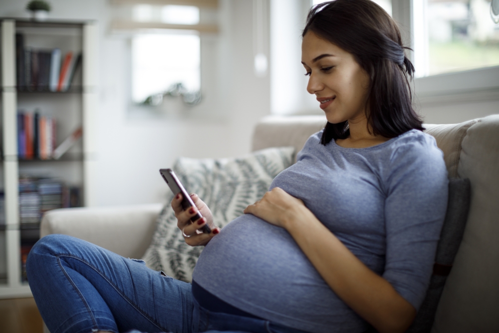 pregnant woman using mobile phone at home