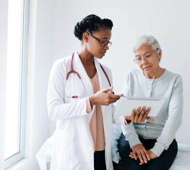 Black female doctor showing digital tablet to senior patient