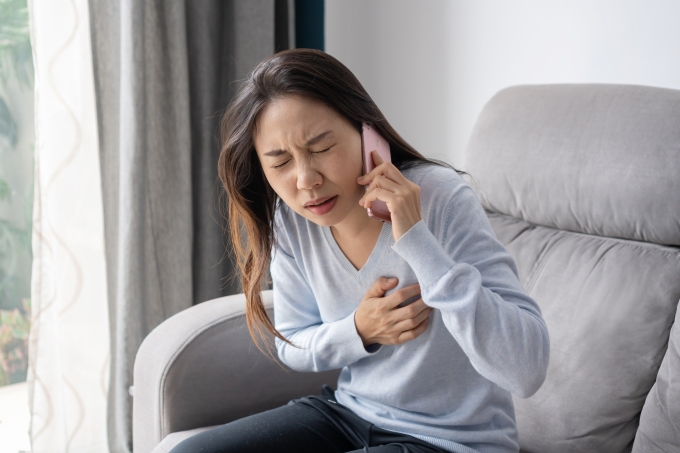 Woman clutching her chest in pain while making a phone call